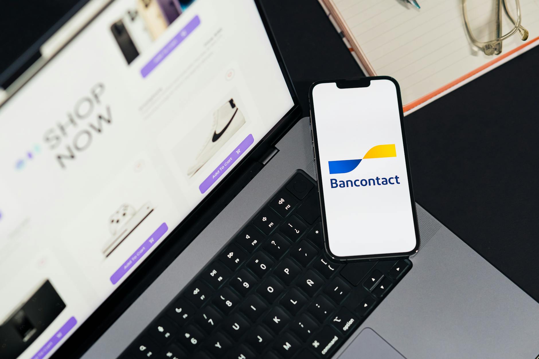 Smartfon z aplikacją płatniczą Bancontact obok laptopa podczas zakupów online