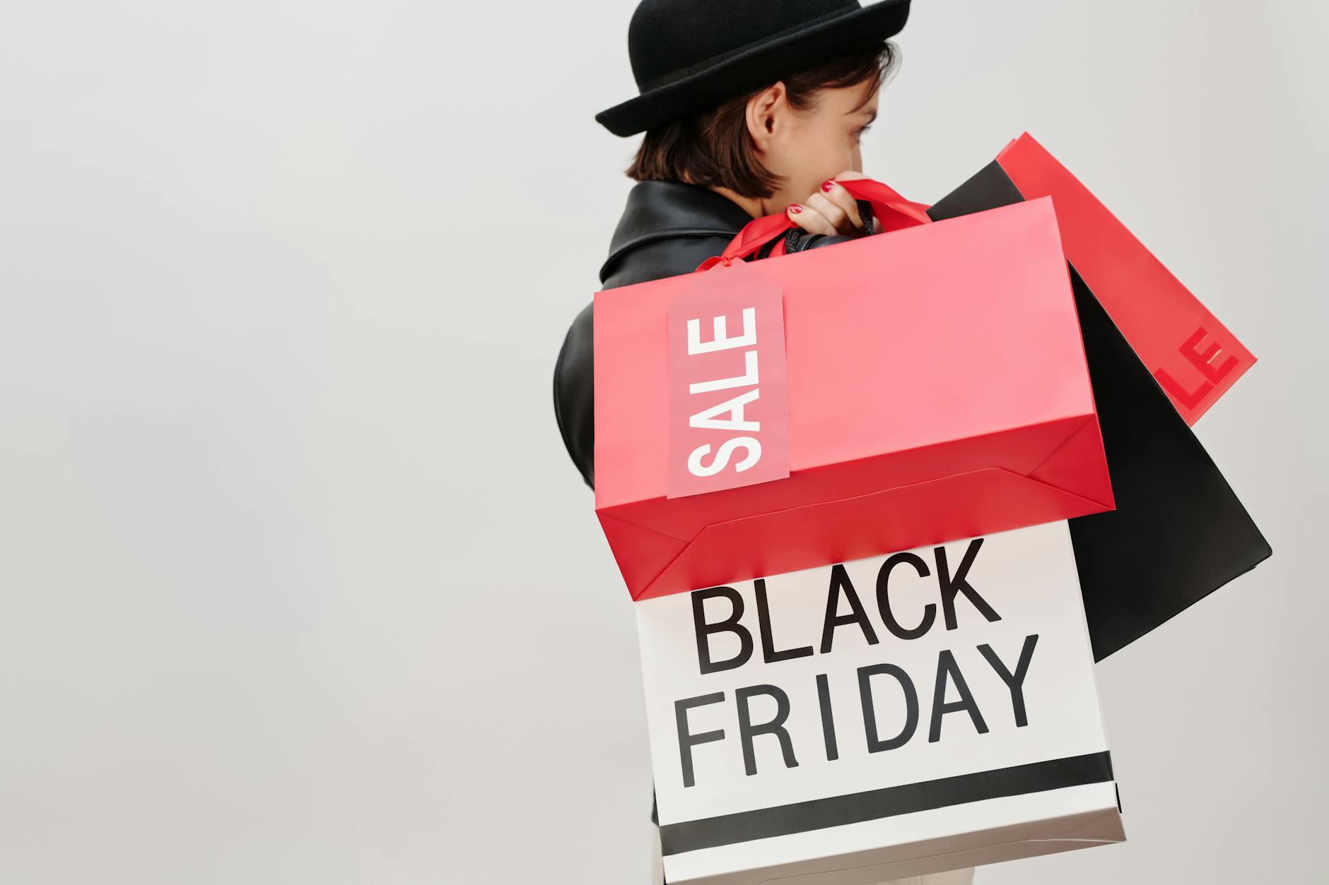 Kobieta z torbami z wyprzedaży Black Friday na neutralnym tle