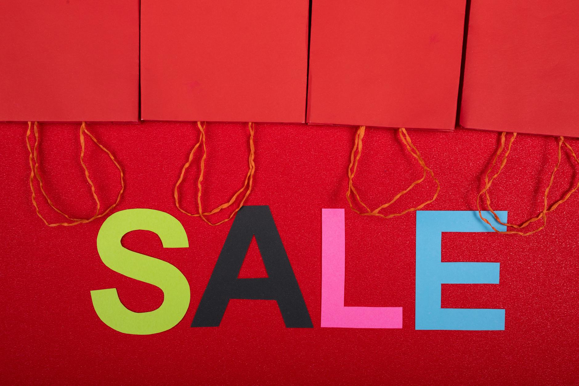 Kolorowy napis SALE i czerwone torby na wyprzedaży sezonowej