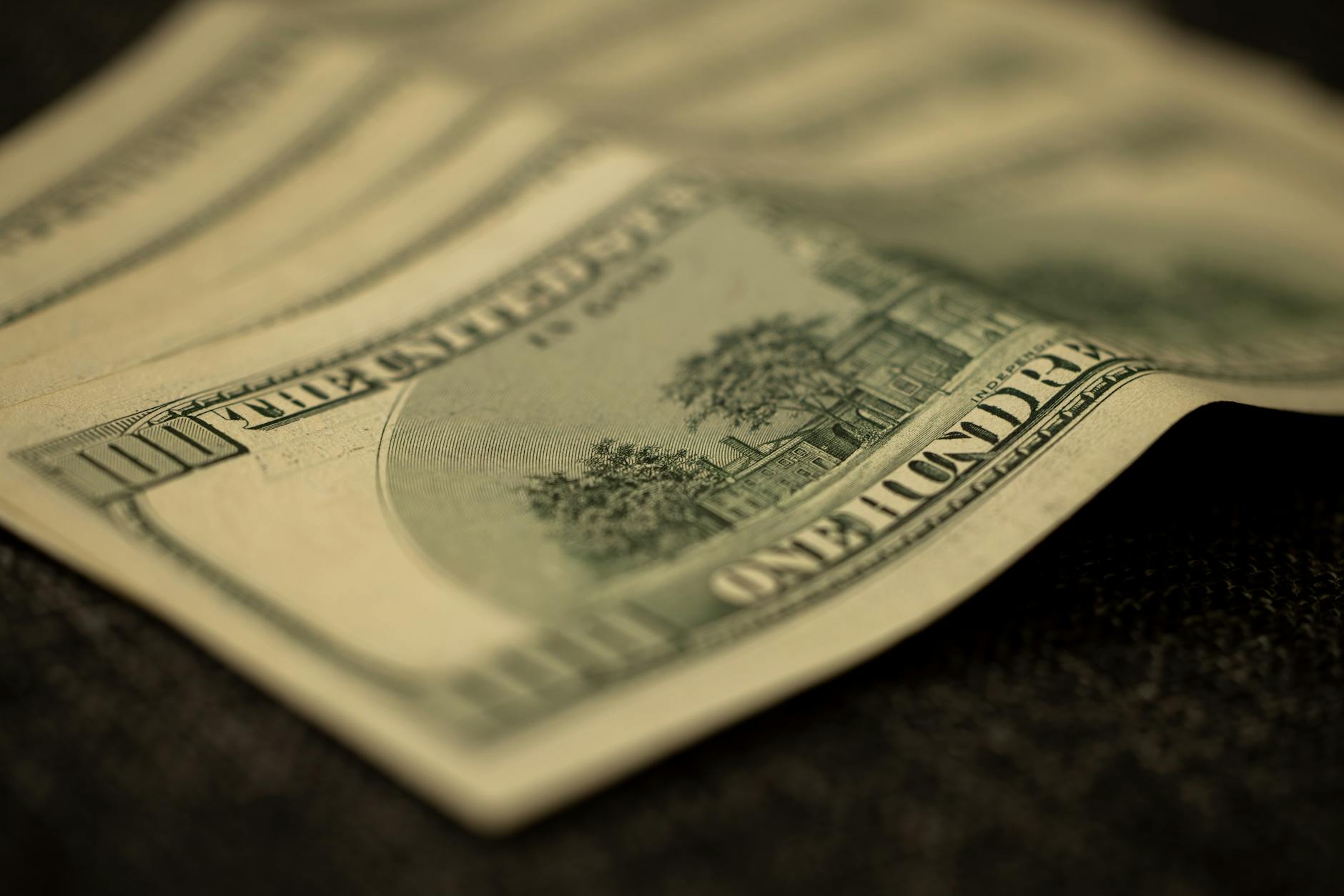 Rozsypane banknoty 100 dolarów symbolizujące zwrot cashback