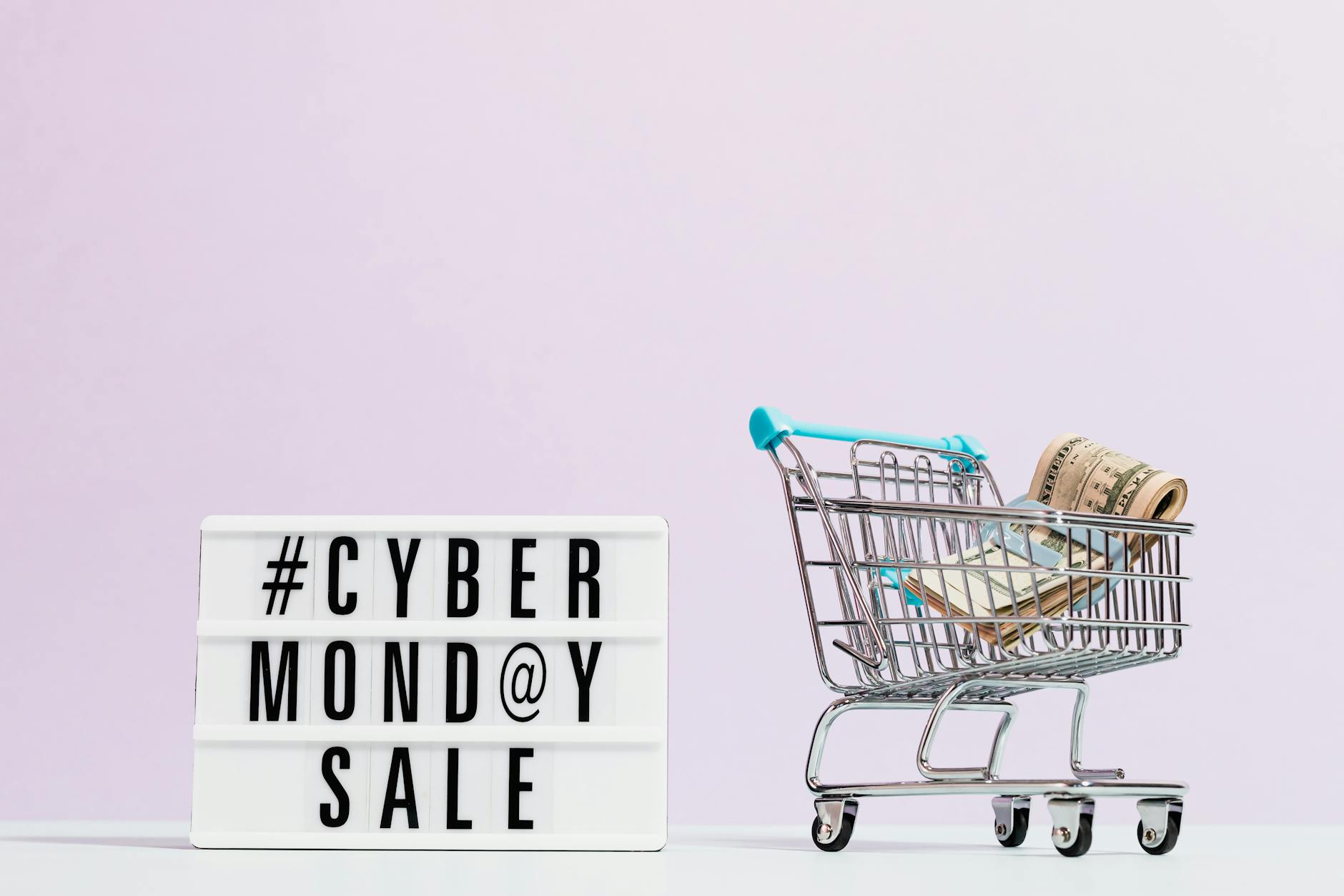Wózek sklepowy pełen gotówki obok tablicy z wyprzedażą Cyber Monday