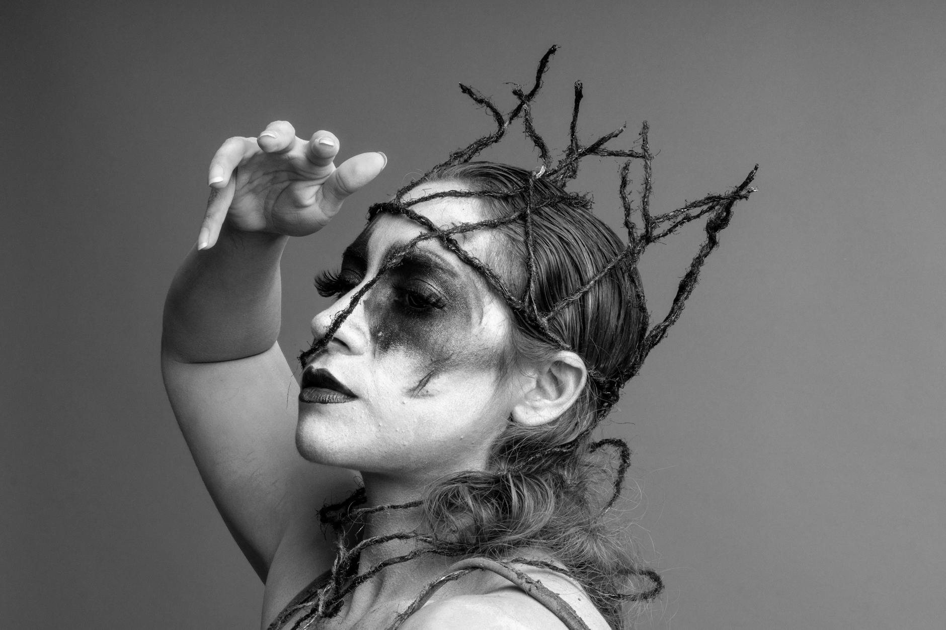 Czarno-biały portret artystki z ekstrawaganckim makijażem i nakryciem głowy