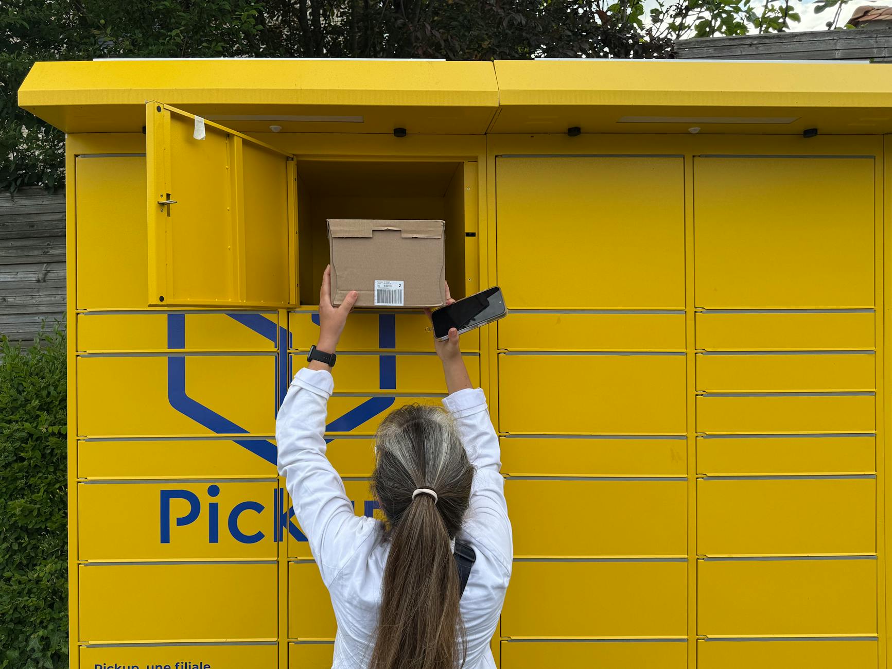 Kobieta odbiera paczkę z żółtego paczkomatu we Francji