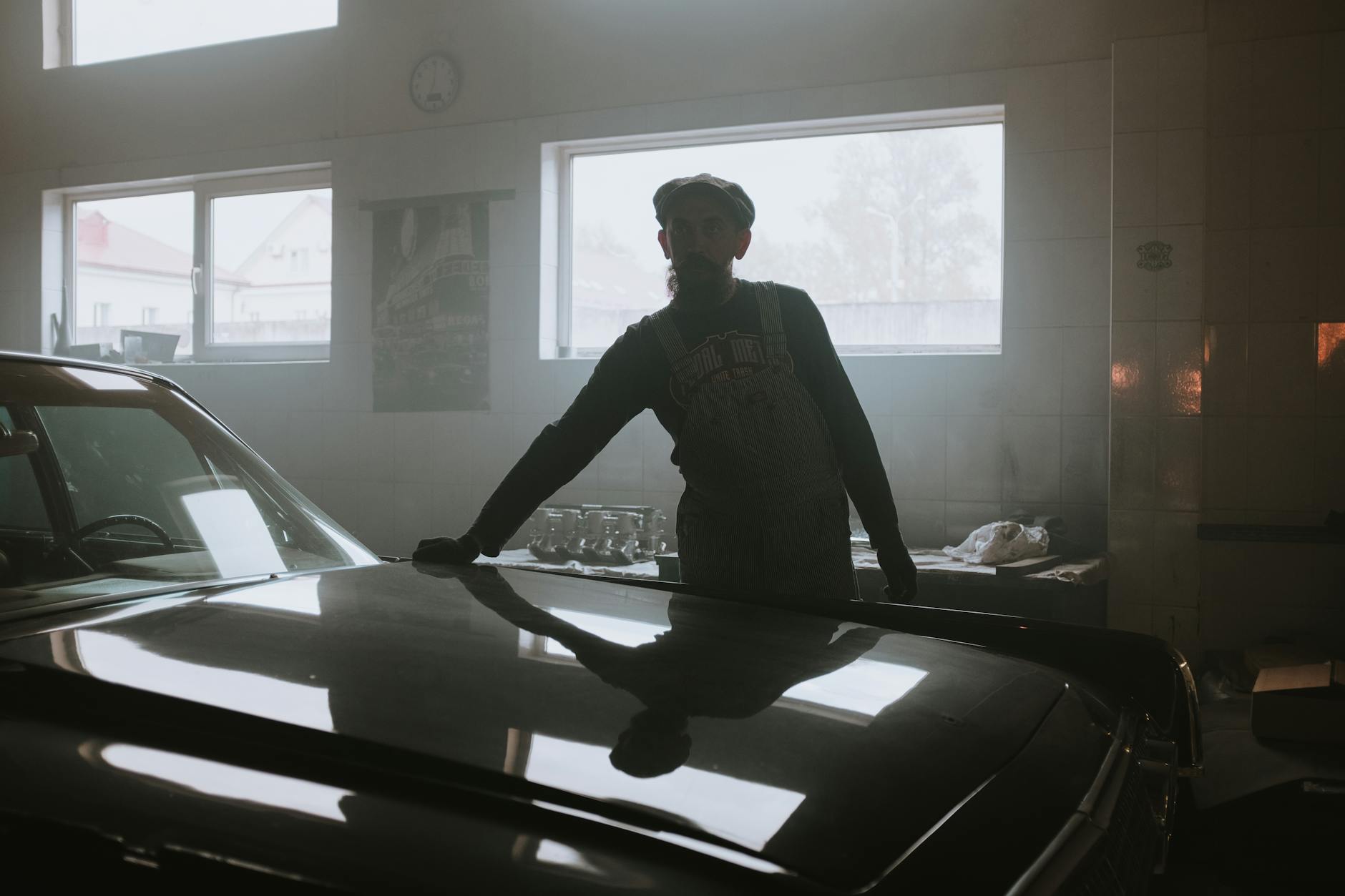 Sylwetka mechanika przy zabytkowym aucie w ciemnym garażu