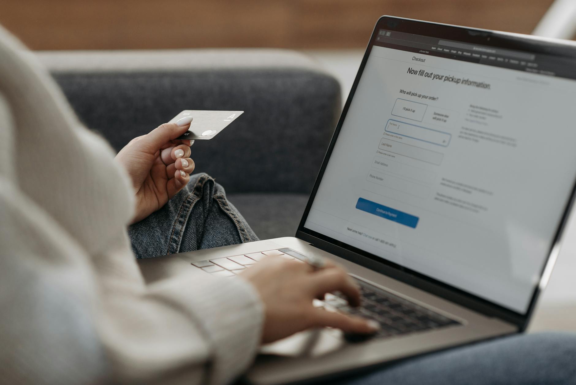 Kobieta na kanapie płaci kartą za zakupy internetowe na laptopie