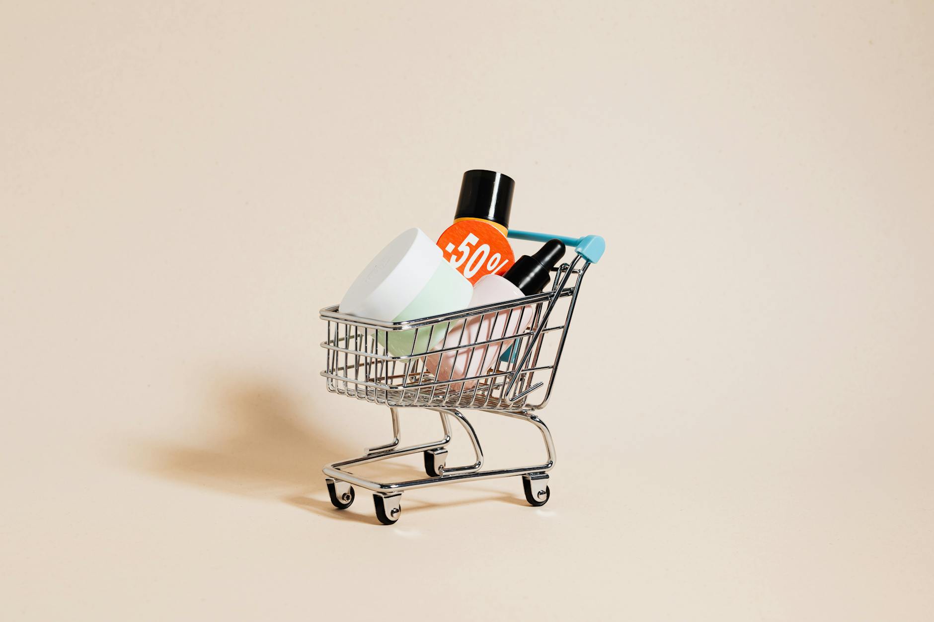 Mini wózek sklepowy z kosmetykami i napisem o 50% rabacie